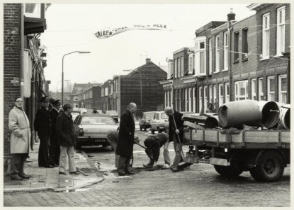Ambtenaren van het bedrijf Openbare Werken verwijderen een afzetting, geplaatst door buurtbewoners om vrachtverkeer tegen te gaan. (i.v.m. verzakking van de huizen). NL-HlmNHA 54011473