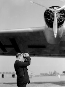 Anthony Fokker met filmcamera bij het vliegtuig Arend op het platform van luch, Bestanddeelnr 190-0080