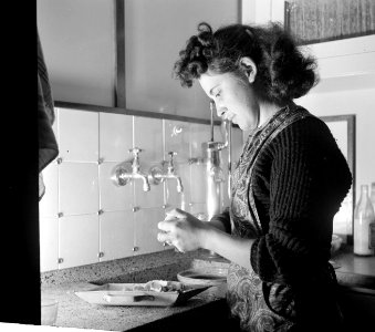 Annie schilt aardappels in een kombuis aan boord van de Damco 9, Bestanddeelnr 254-1435