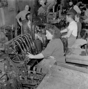 Arbeiders bezig met het vullen van wijnflessen aan een vulmachine in de Rothschi, Bestanddeelnr 255-1606