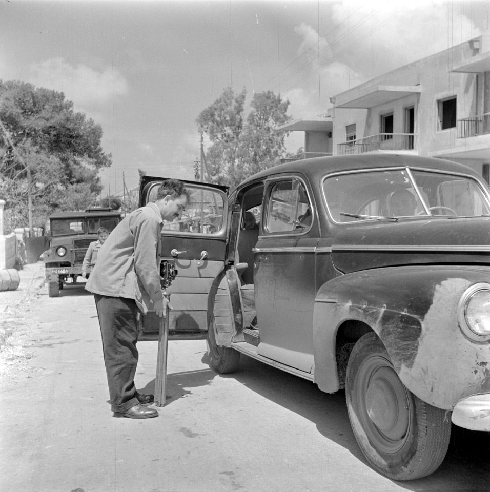 Arnold Berger met fotouitrusting bij een personenauto, Bestanddeelnr 255-1422