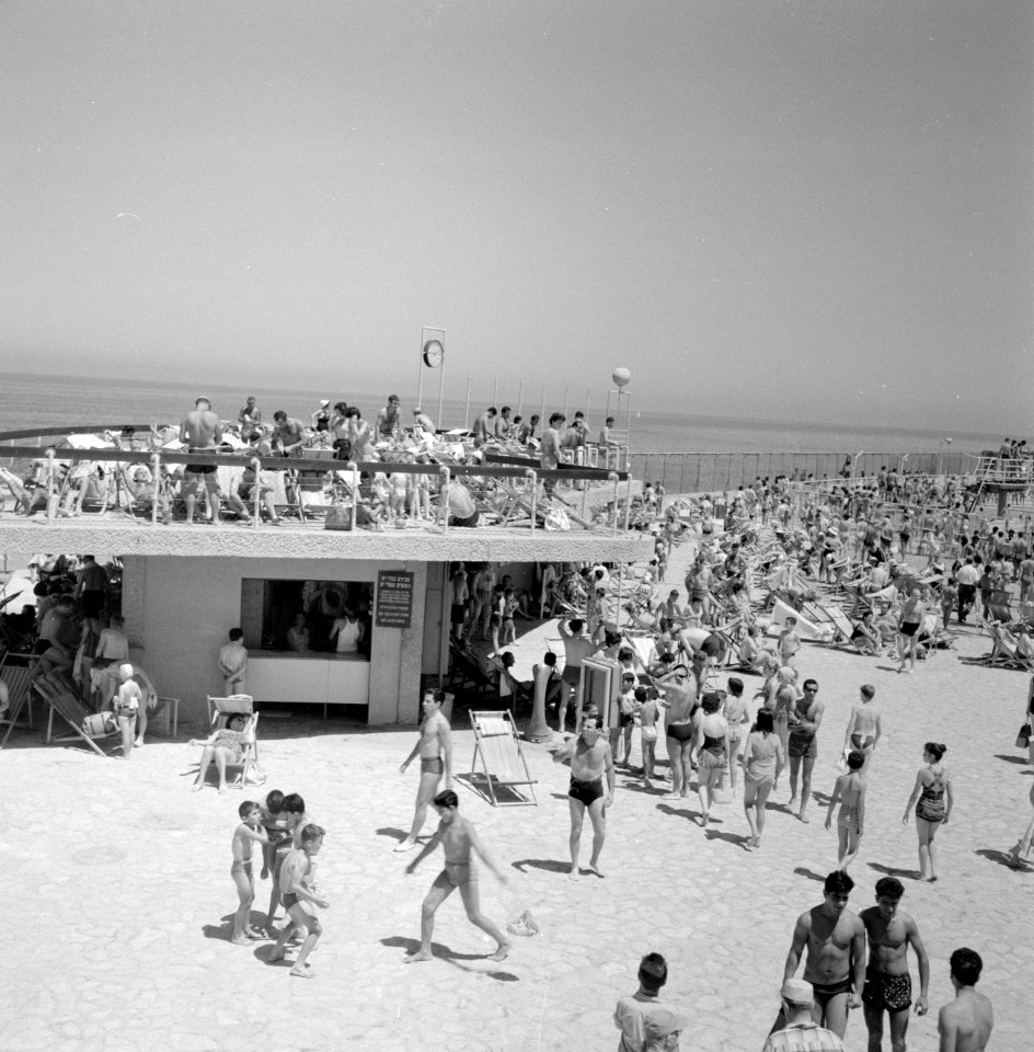 Badgasten liggen in strandstoelen te zonnebaden in het zand en op het dak van ee, Bestanddeelnr 255-1951