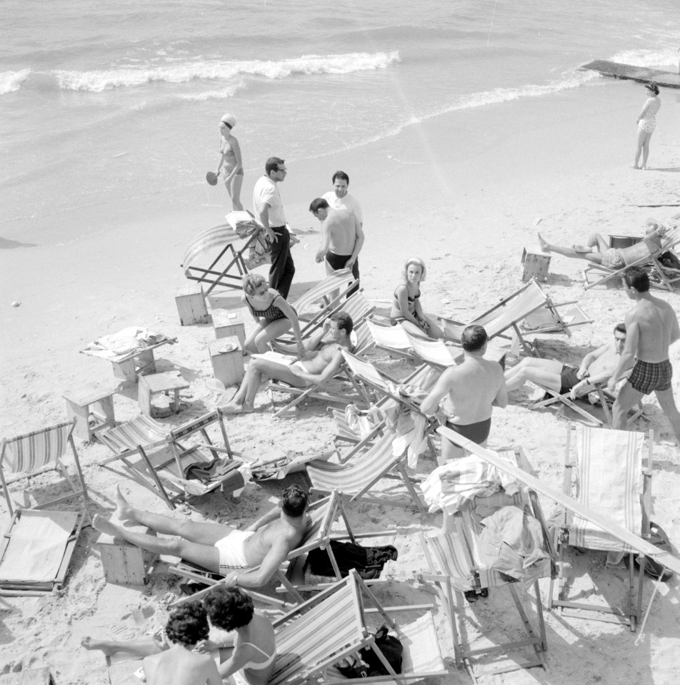 Badgasten en strandstoelen op het strand (in de branding van de zee spelen mense, Bestanddeelnr 255-1944