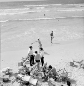 Badgasten en strandstoelen op het strand (in de branding van de zee spelen mense, Bestanddeelnr 255-1949