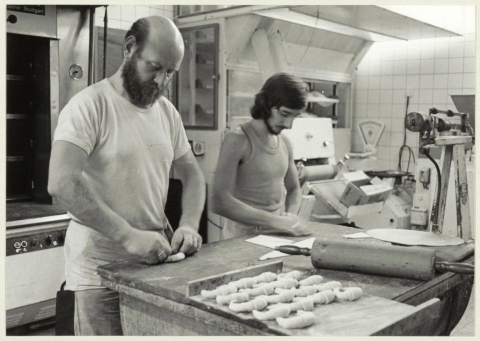 Bakker H. van Asselt en medewerker aan het werk in de bakkerij in de Theemsstraat 60. NL-HlmNHA 54009607
