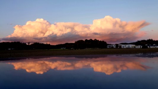 Bank of pink clouds reflected in the roof of a blue car photo