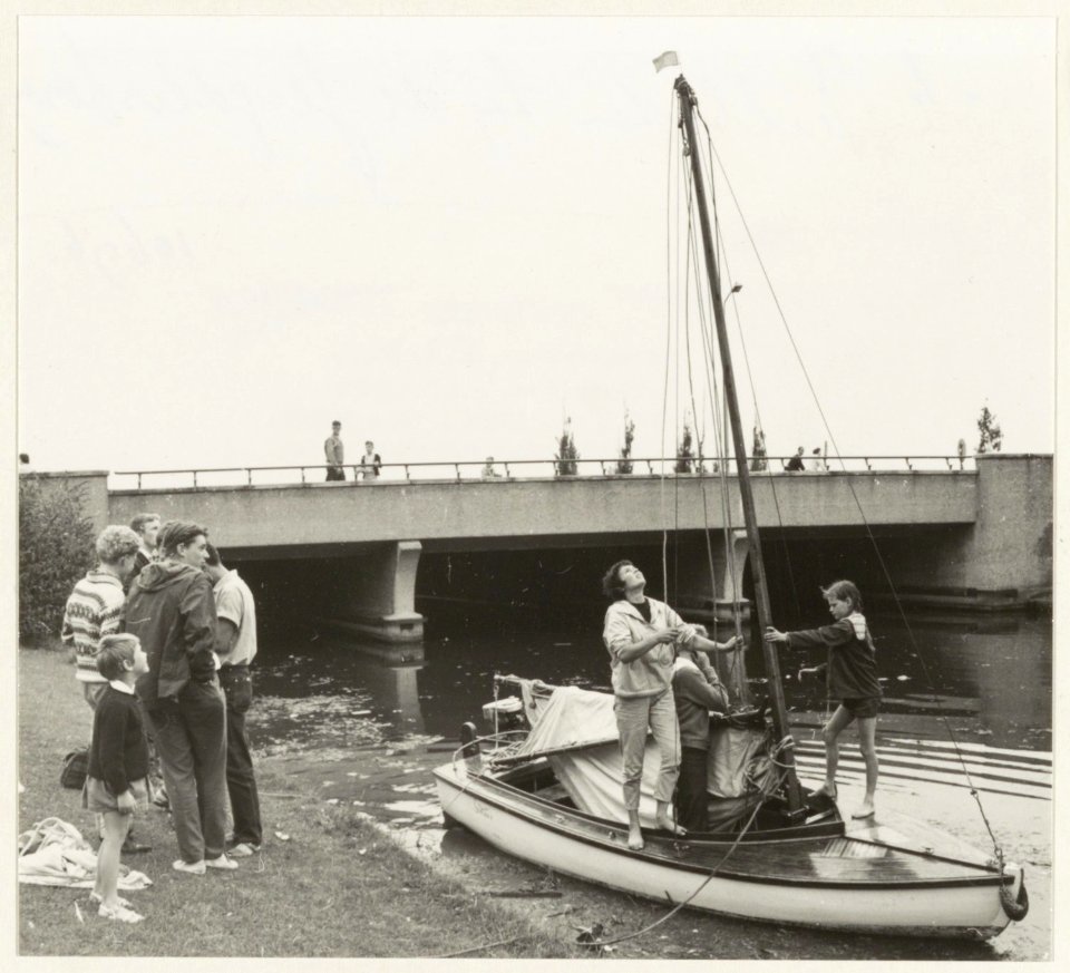 Bezoekers per zeilboot in de Jan Gijzenvaart voor de jeugdherberg. Op de achtergrond de Sinneveltbrug. NL-HlmNHA 54010696