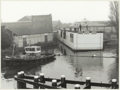 Bewoners van de Harmenjanswijk blokkeren uit protest het Spaarne, hun uitgebrande wijkcentrum De Brug als barrière gebruikend, omdat ze vonden dat het herstel te lang uitbleef. Links een b, NL-HlmNHA 54012596