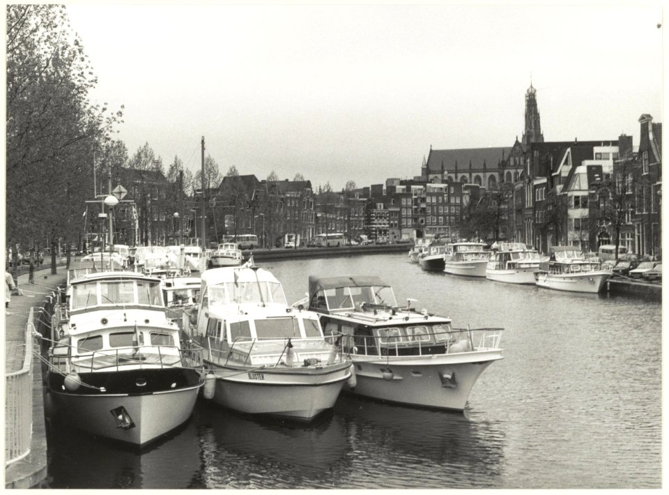 Bezoek van de Koninklijke Nederlandse Motorboot Club aan Haarlem. De schepen liggen afgemeerd in het Spaarne ter hoogte van de Turfmarkt. NL-HlmNHA 54023746
