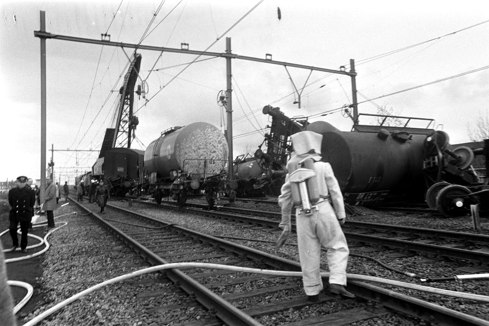 Beschadigde tankwagons worden met hijskranen geborgen, brandweerman in hitte bes, Bestanddeelnr 923-4817