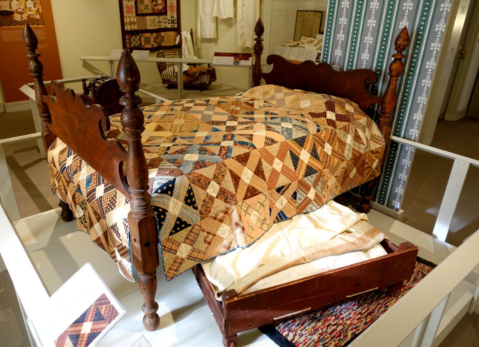 Bedstead, New England, 1820-1840, grain-painted wood, with quilt, Concord, 1847-1849, calico, cotton, and trundle bed, New England, 1820-1840, maple, pine - Concord Museum - Concord, MA - DSC05874