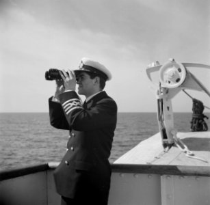 Bemanningslid van een schip, kijkend door een verrekijker, Bestanddeelnr 255-0005