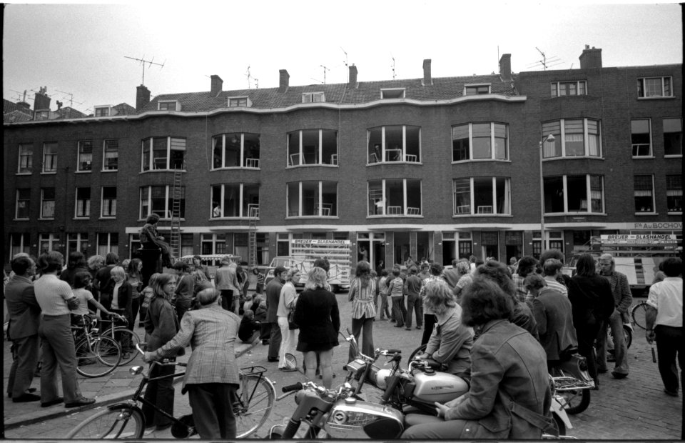 Belangstellend publiek kijkt naar reparatie ramen in Wapenstraat na rellen in Afrikaanderwijk 1972