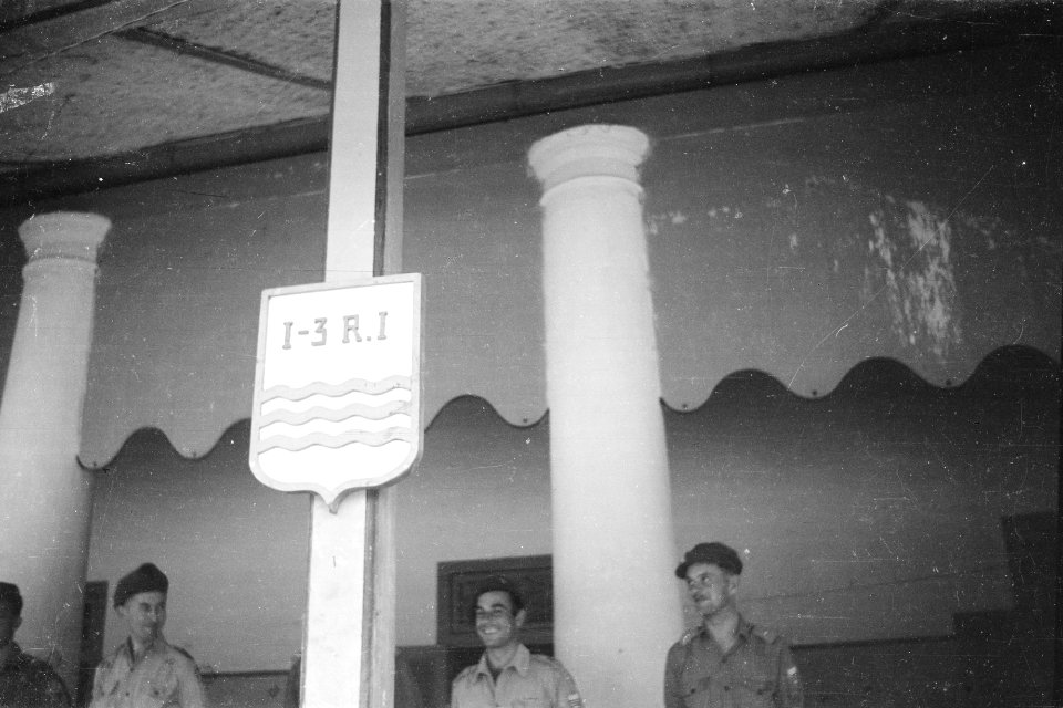 Bord bevestigd aan pilaar van veranda van een groot gebouw met wapen van I-3 R.I, Bestanddeelnr 336-6-7