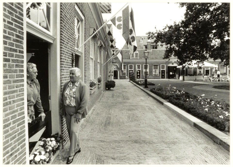 Binnentuin Hofje van Staats met Friese en Hollandse vlaggen aan de gevels. NL-HlmNHA 54032117