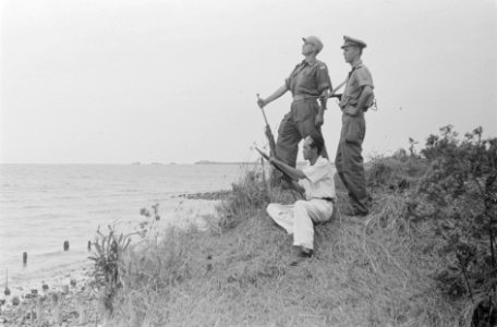 Bij de zee, aan de kust, poseren twee militairen met een -Chinese- burger die…, Bestanddeelnr 32-2-3