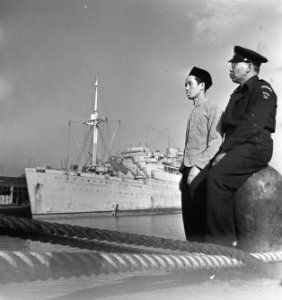 Bijschrift Two Indonesian member of the Dutch liner seen in the background. , Bestanddeelnr 935-3136