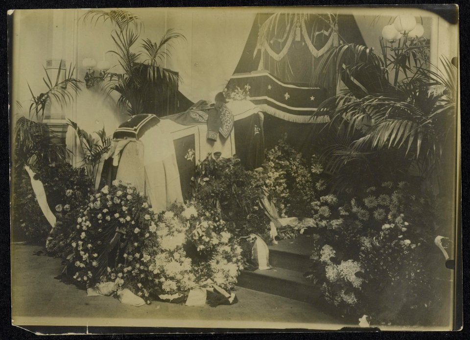 Bloemen, ambtskleding en onderscheidingen rondom de gesloten lijkkist van een op, Bestanddeelnr 158-1232