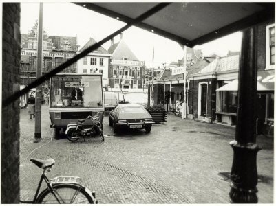 Blik over de Grote Markt vanuit de Lepelstraat, met de panden van Brinkman, de Hoofwacht en de Vishal, tijdens de markt. NL-HlmNHA 54008405