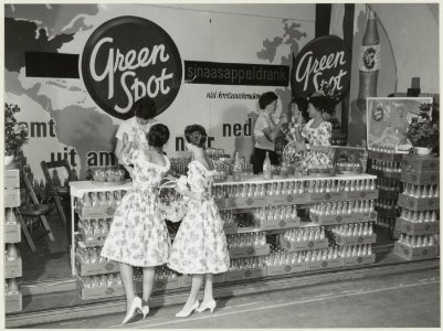 Bloemenmeisjes bij de stand van de Amerikaanse frisdrankfabrikant Green Spot op de Haarlemse voorjaarsbeurs in het Krelagehuis. NL-HlmNHA 54010545