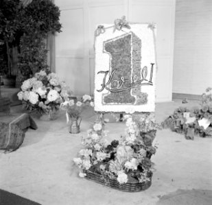 Bloemstukken in manden en het logo van sigarenmerk Karel I op een schildersezel , Bestanddeelnr 255-8486