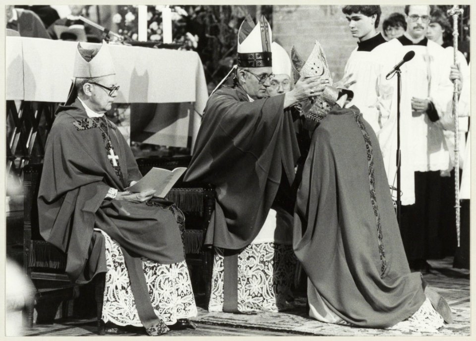 Bisschop Bomers zet de mijter op het hoofd van zijn hulpbisschop monseigneur Lescrauwaet, in de Kathedraal St. Bavo. NL-HlmNHA 54014444