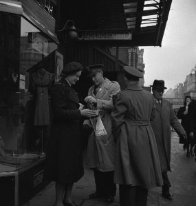 Buitenlandse officieren kopen speldjes van een lid van het Vrouwen hulpkorps, Bestanddeelnr 935-2406