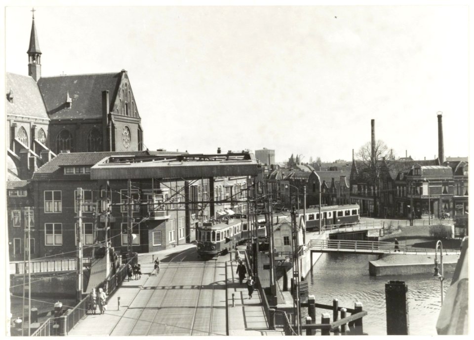 Budapester stel van de NZH (blauwe tram) is net de Langebrug gepasseerd en rijdt via Antoniestraat richting Herensingel, op weg naar Amsterdam. Links is een deel van de Spaarnekerk te zien