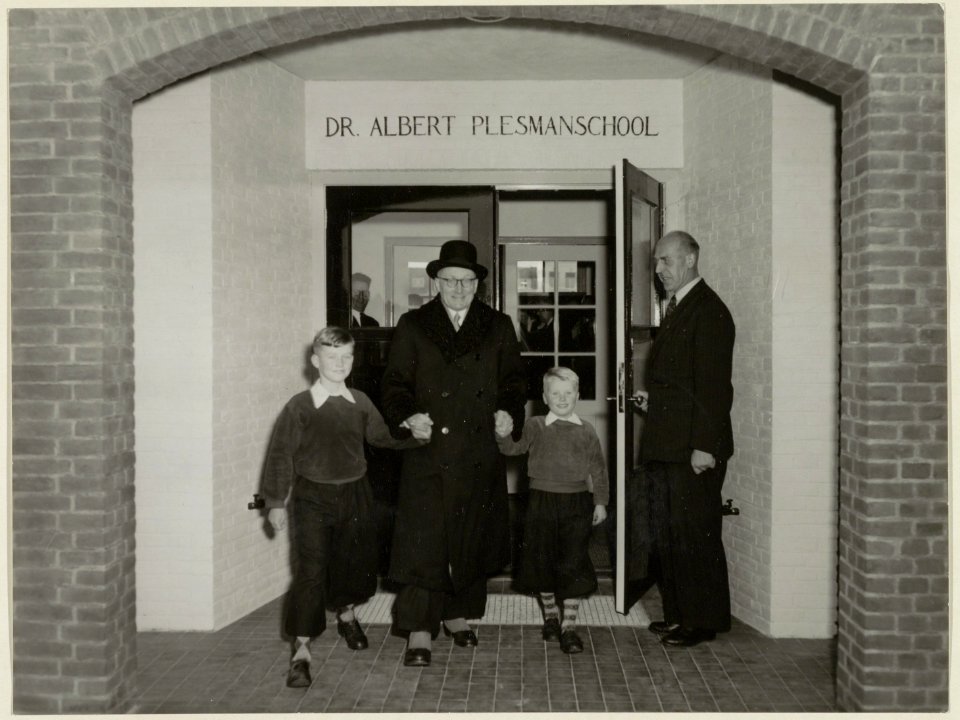 Burgemeester H. van Fenema, de hoofdonderwijzer en twee leerlingen bij de opening van de Dr. Albert Plesmanschool. NL-HlmNHA 54004204