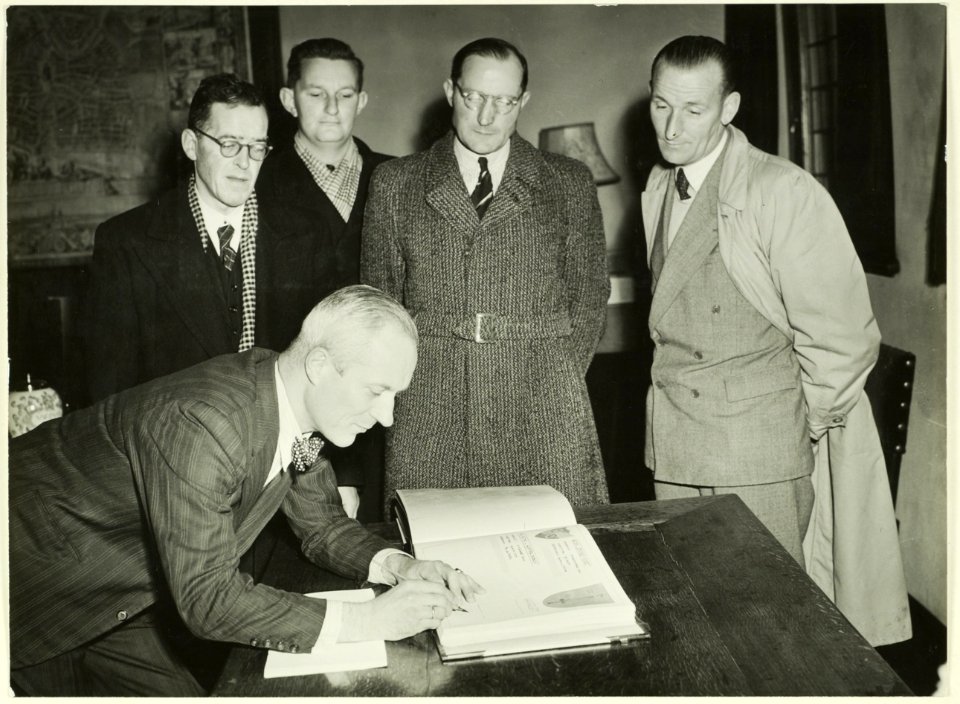 Burgemeester Mr. O.P.F.M. Cremers van Haarlem tekent een gedenkboek van de Nederlandse Wandelsport Bond dat aan Kon. Juliana zal worden aangeboden. NL-HlmNHA 5400466862