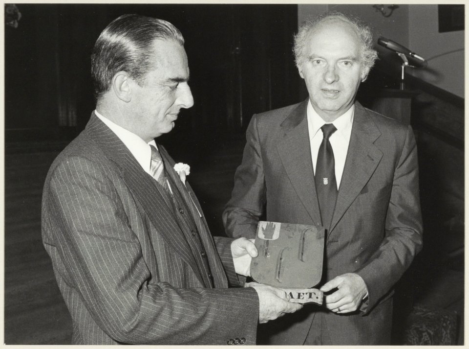 Burgemeester F.G.L.L. Schols van Den Haag overhandigt aan de heer Vermaire (links) de 14 wapenborden van de fam. De Raet, in de Gravenzaal van het stadhuis. NL-HlmNHA 54012624