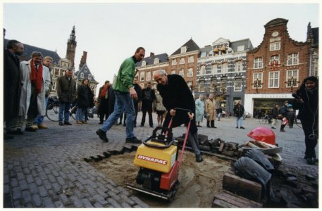 Burgemeester Pop is druk in de weer met een trilplaat. hij gaf hiermee het startsein voor de herbestrating van de Grote Markt. NL-HlmNHA 54037062