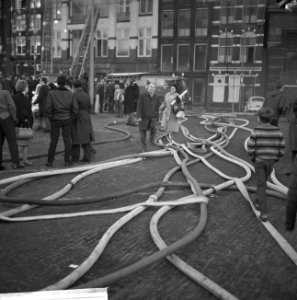 Brandslangen die over de straat liggen jongen wandelend over een van de brandsl, Bestanddeelnr 918-4090