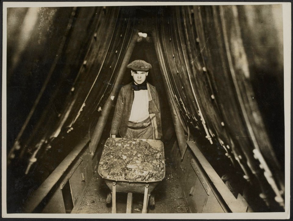 Boy bringing coal from the bunkers through a gangway between two boilers, Bestanddeelnr 158-2645