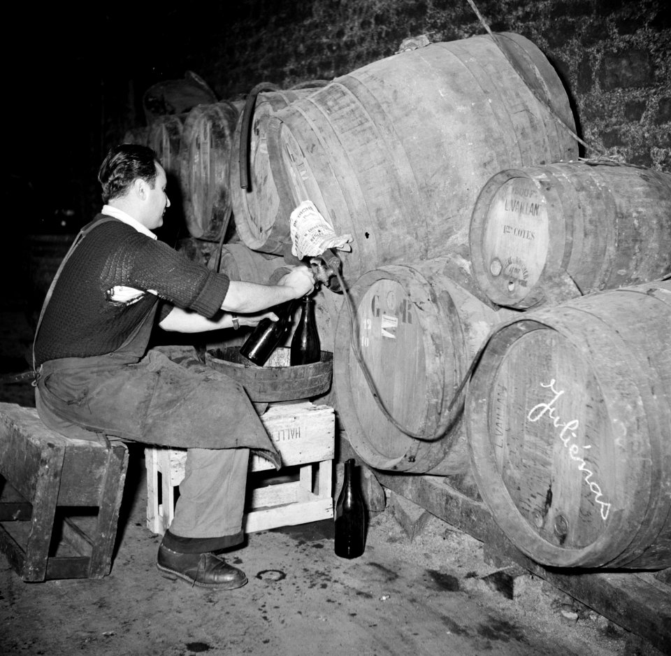 Bottelarij man tijdens het tappen van wijn uit een vat, Bestanddeelnr 252-9439