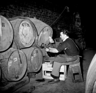 Bottelarij man tijdens het tappen van wijn uit een vat, Bestanddeelnr 252-9438