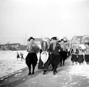 Bruidspaar met daarachter een muziekkorps, allen in klederdracht. De bruidegom m, Bestanddeelnr 254-1937
