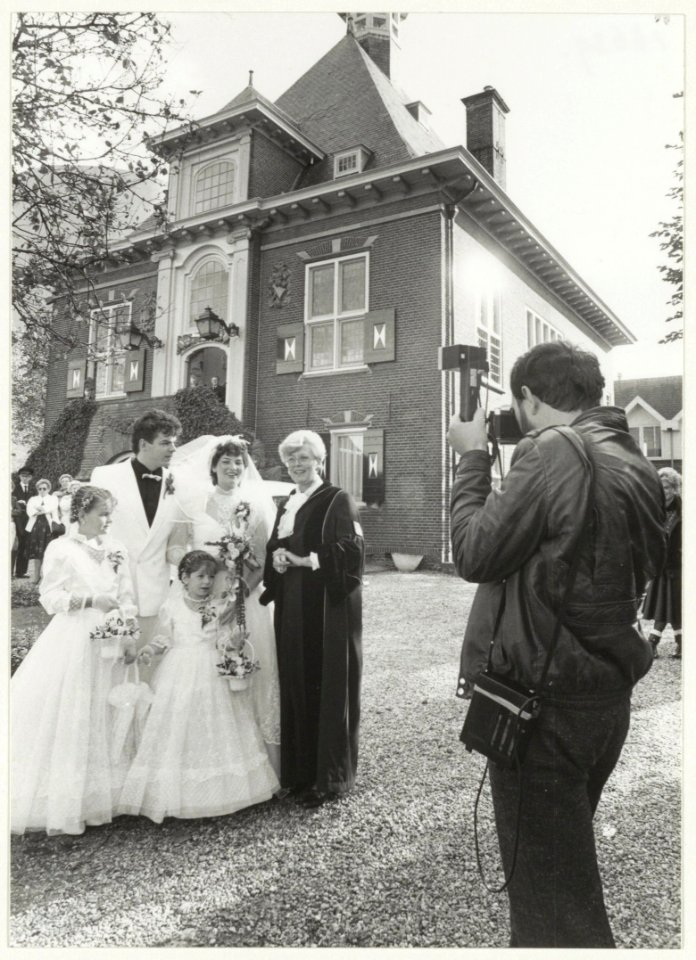 Bruidspaar Blom-Smit met de ambtenaar van de burgelijke stand, mevrouw G.N. de Jongh-de Vries voor het gemeentehuis in Halfweg., NL-HlmNHA 54016639
