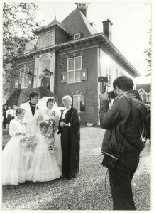 Bruidspaar Blom-Smit met de ambtenaar van de burgelijke stand, mevrouw G.N. de Jongh-de Vries voor het gemeentehuis in Halfweg., NL-HlmNHA 54016639