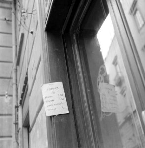 Briefje met tarieven aan de deurpost van een kapperszaak, Bestanddeelnr 191-1268