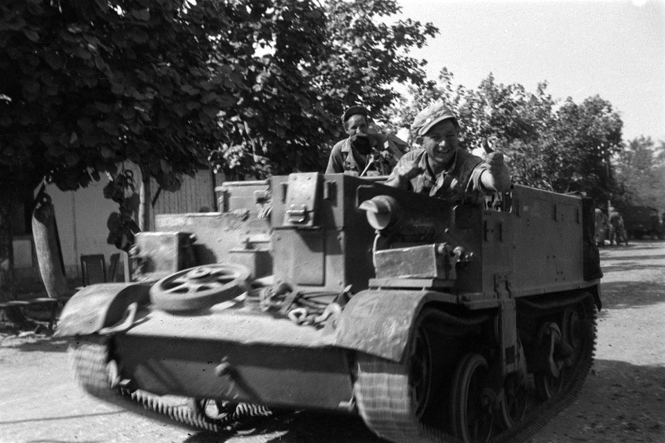 Bren-carrier met bemanning rijdt over een hoofdweg door een stad. Militair steek, Bestanddeelnr 4451