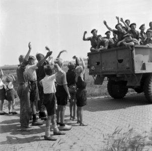 Canadese militairen in de laadbak van een vrachtwagen zwaaien naar kinderen, Bestanddeelnr 900-5474