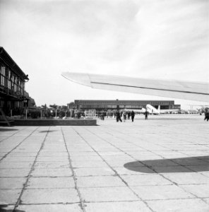 Café-terras De wijde blik met op de achtergrond een grote hangar en een gepark, Bestanddeelnr 254-2412