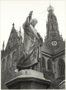 Close-up van het standbeeld van Lourens Jansz. Coster met de Grote Kerk als achtergrond. NL-HlmNHA 54021230