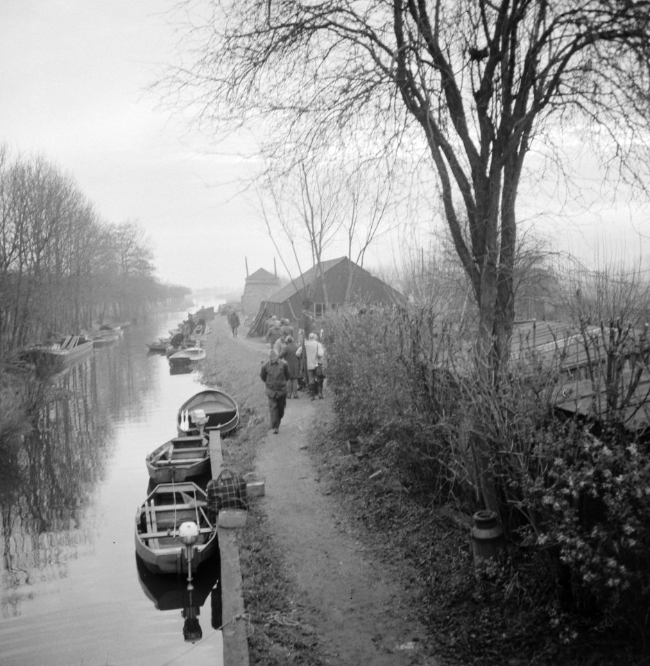 Club van honderd (vissen) mensen lopend langs een vaart of riviertje met aan d…, Bestanddeelnr 918-5695