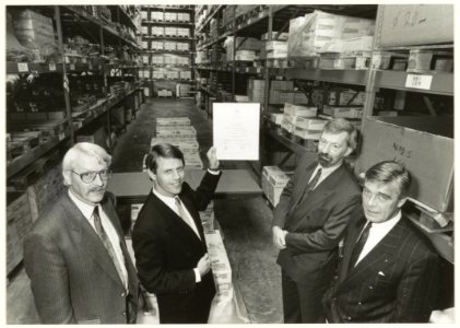 Chris Vrijmoed, Rik Brinkman en Joop van den Berg en links de heer Venis van Lloyd met een certificaat van kwaliteitsbeheersing volgens ISO standaard. NL-HlmNHA 54032138