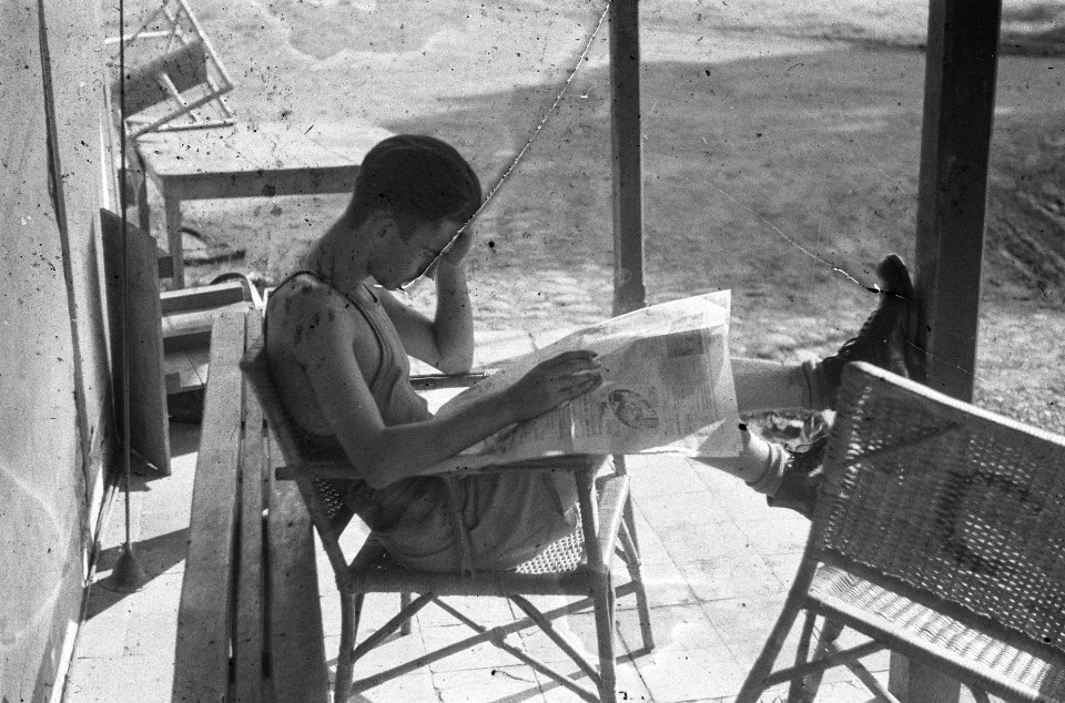 Cheribon. Een Nederlandse militair leest een krant gezeten op een veranda, Bestanddeelnr 390-4-1