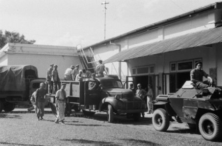 Colonne voertuigen aangevoerd door een scoutcar maakt zich klaar bij een gebouw, Bestanddeelnr 382-6-6