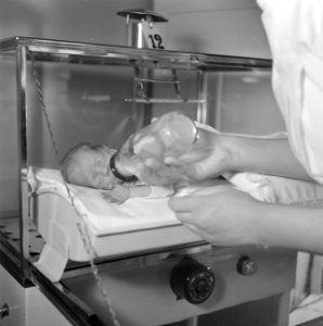 Couveusebaby Caspar krijgt de fles van een verpleegster, vermoedelijk in het Sin, Bestanddeelnr 254-2538