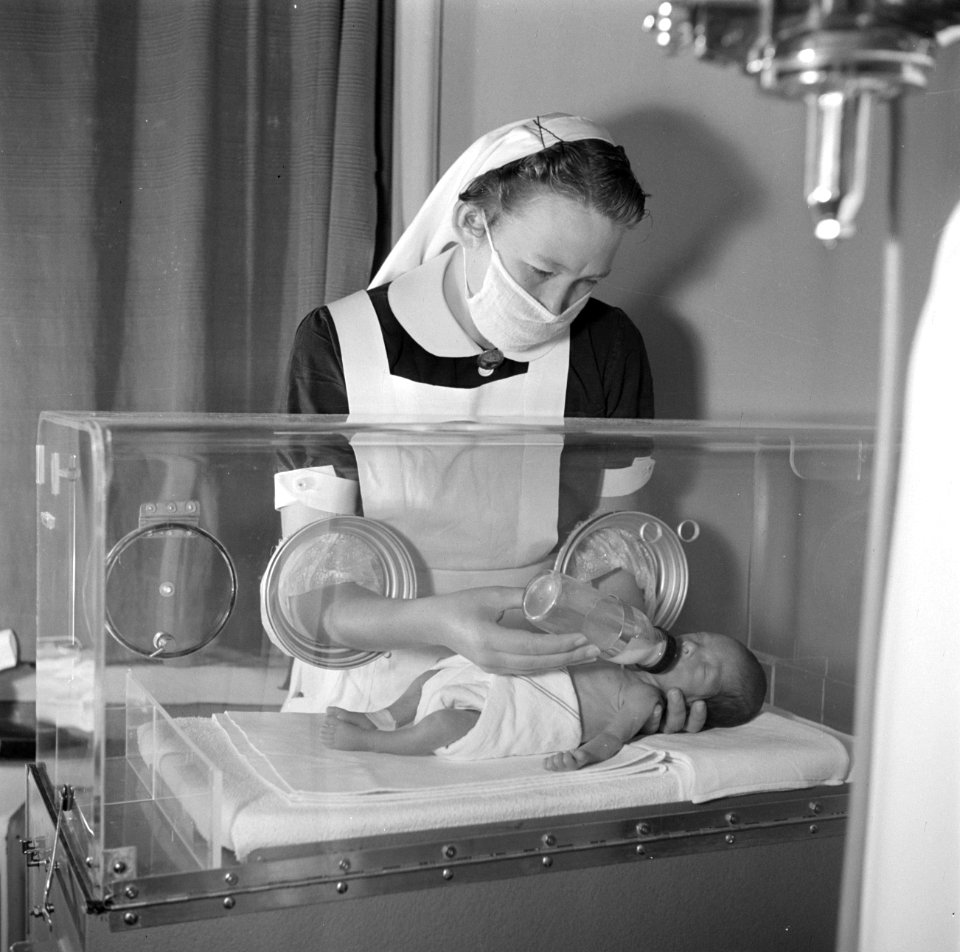 Couveusebaby Martin krijgt de fles van een verpleegster, vermoedelijk in het Sin, Bestanddeelnr 254-2532